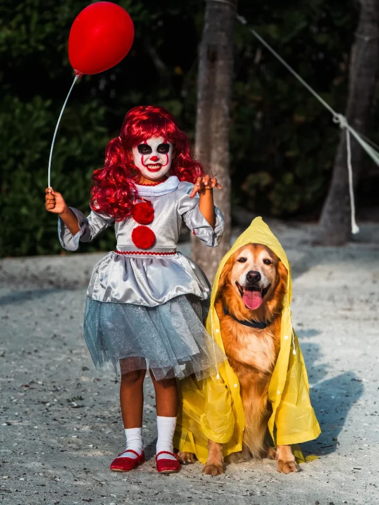 13. Pennywise-Inspired Clown Costume with Balloon and Raincoat Dog Duo Outdoors at Dusk