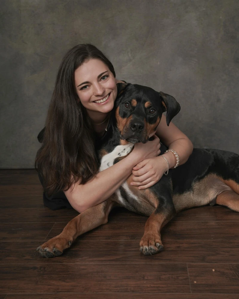 Collarless Rottweiler Mix Hugging His Owner on a Dark Wood Floor