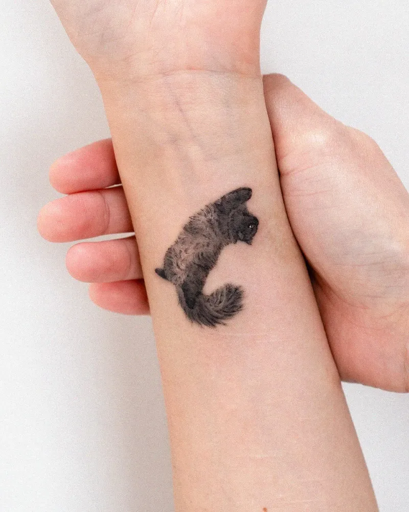 Fluffy Dark Grey Cat Mid-Leap Micro-Realism Tattoo on the Inner Wrist
