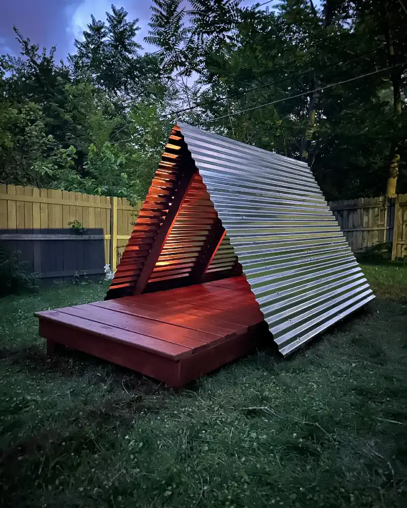 Modern A-Frame Shelter with Corrugated Metal Roofing and Red-Stained Decking