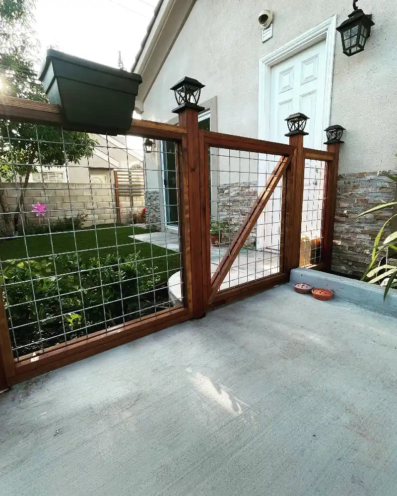 Stained Wood Frame Hog Wire Gate with Solar Cap Lights on Concrete Patio