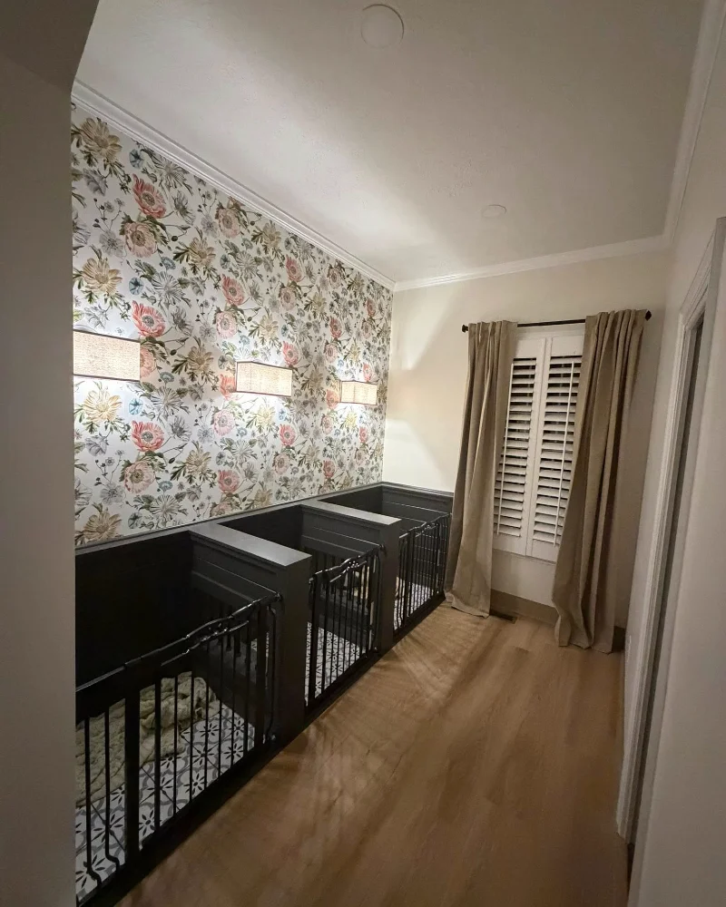 Triple Built-In Charcoal Dog Kennels with Floral Wallpaper and Warm Fabric Sconces