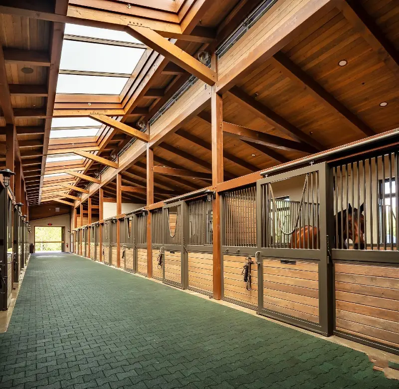 Cathedral-Style Stable Corridor with Emerald Pavers and Expansive Skylight Roof