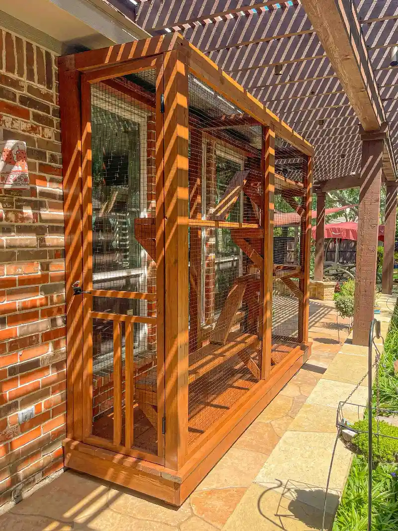 Cedar-Stained Slim Catio Against Red Brick Wall Under Pergola Shadows