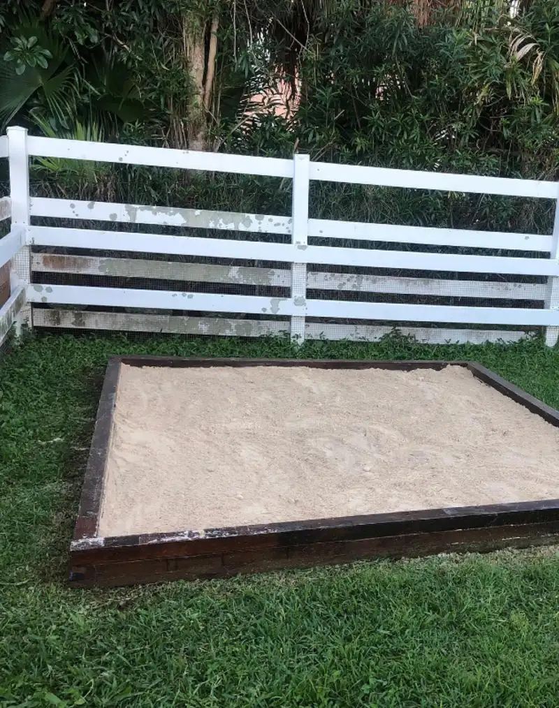 Dark-Stained Timber Sandbox in Front of a White Rail Fence