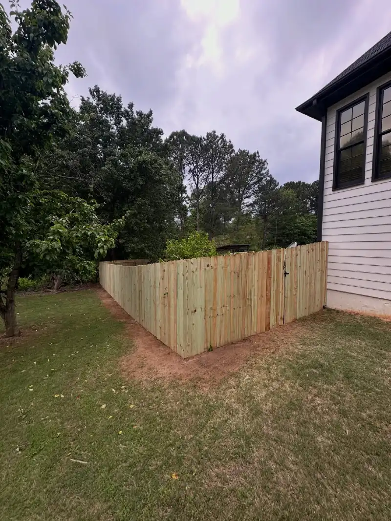 Dog-Ear Pressure-Treated Wood Privacy Fence along a Grassy Slope