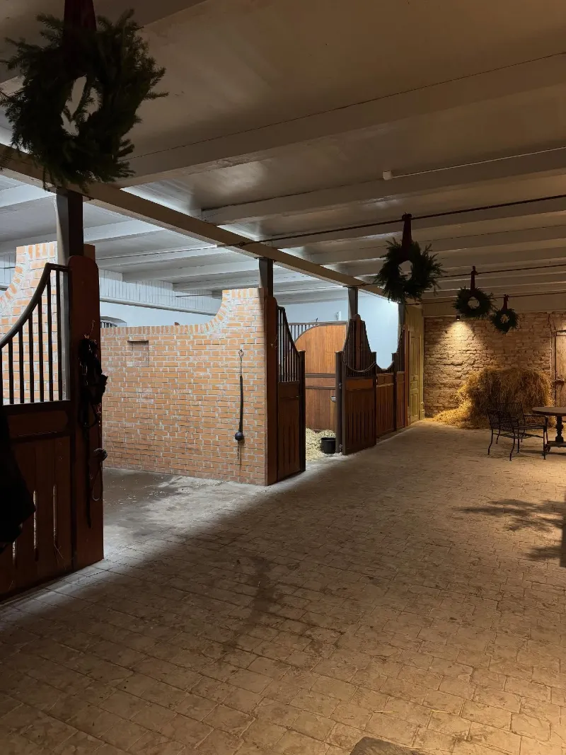 Festive Evergreen Wreaths Hung from Ceiling Beams in a Brick Barn
