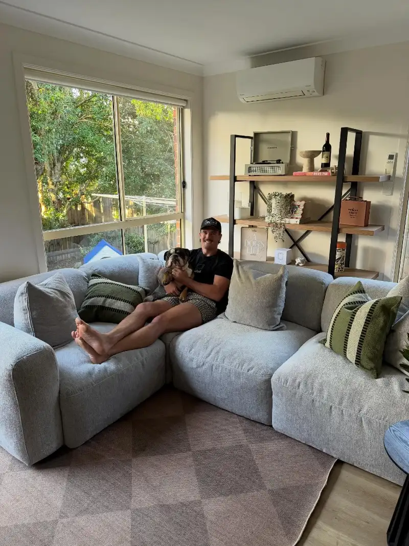 Grey Textured Modular Sectional with Olive Green Striped Cushions and Open Wooden Bookshelf