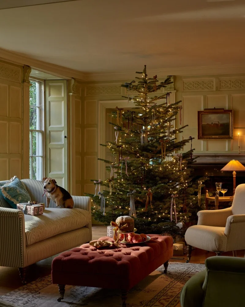 Historic Paneled Parlor with Ribbon-Adorned Tree and Tufted Terracotta Ottoman