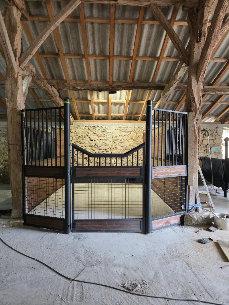 Industrial Black Mesh Stall Gate Against a Heritage Stone Backing