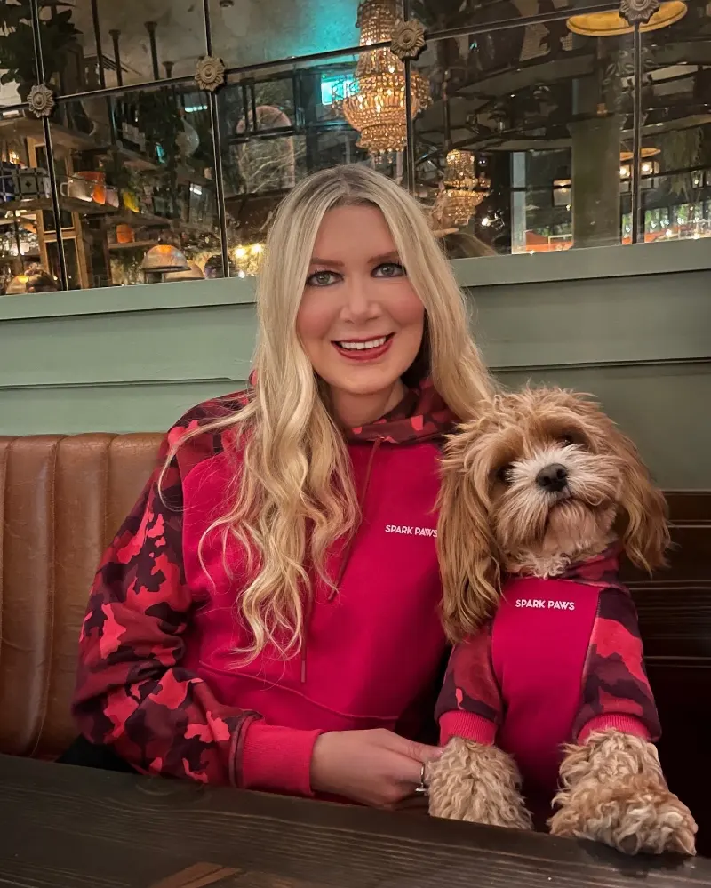 Magenta and Red Camouflage Hoodies on a Blonde Woman and Her Cavapoo