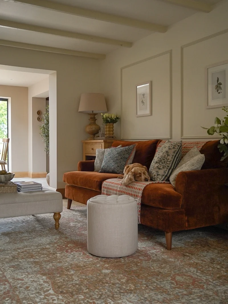 Rust Velvet Sofa with Patterned Throw Blanket and Tufted Round Pouf