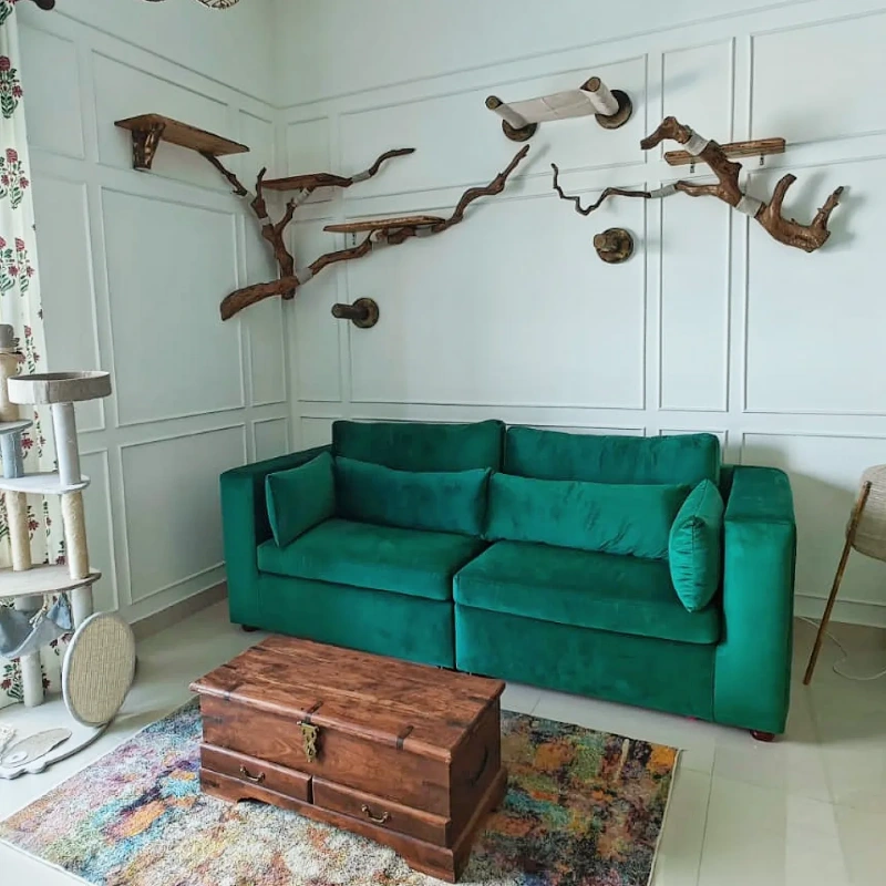 Sculptural Driftwood Wall Branches Mounted Above a Vibrant Emerald Velvet Sofa