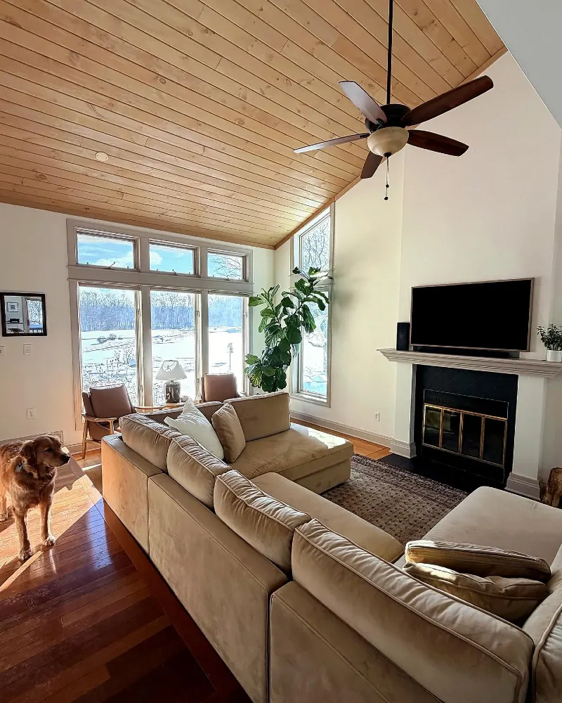 Tan Microfiber Sectional with Sloped Wooden Ceiling and Traditional Brick Fireplace