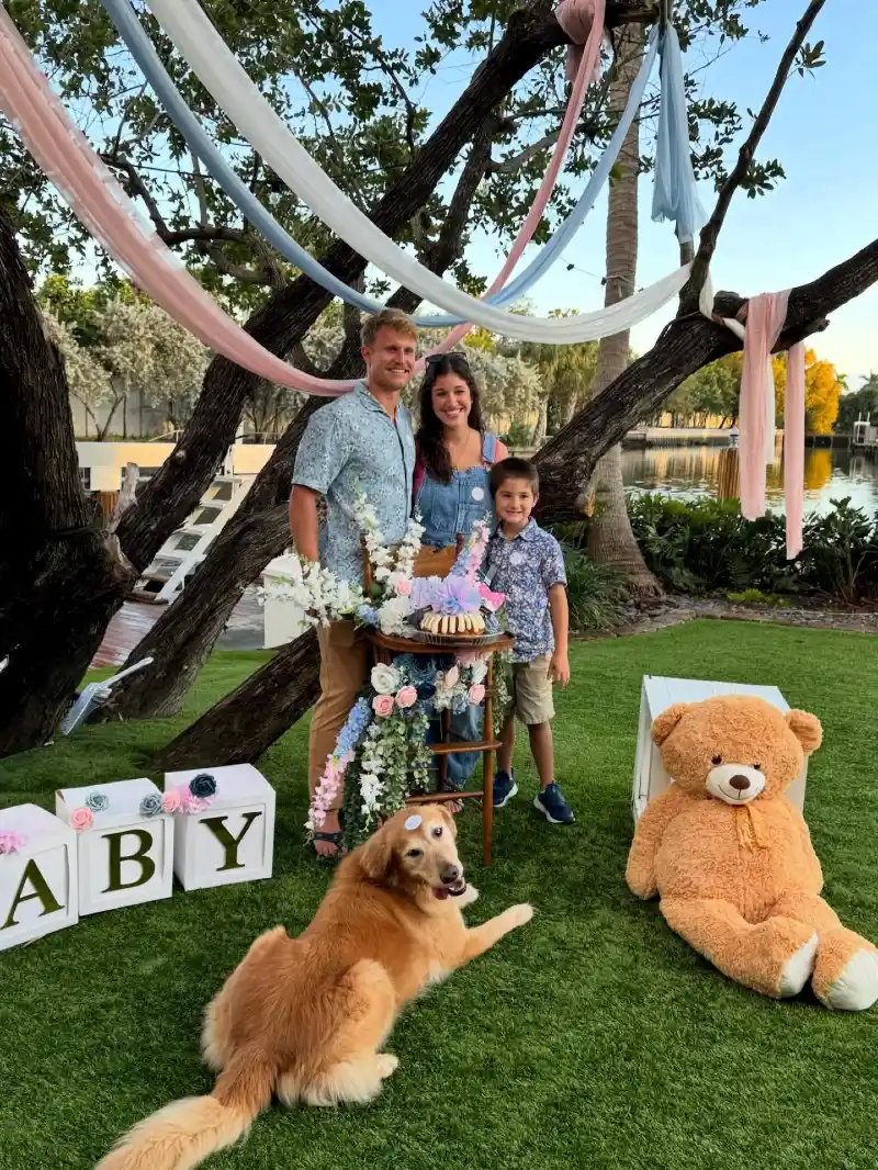 Family Standing Under Draped Fabric Banners with a Golden Retriever on the Grass