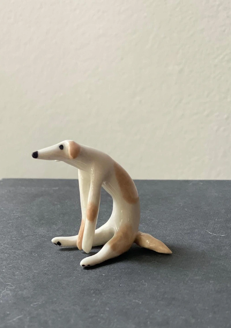 Miniature Glazed Ceramic Dog Figurine on Dark Surface