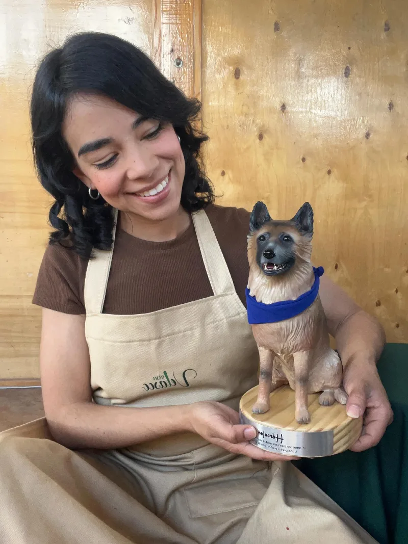 Smiling Artisan Holding Custom German Shepherd Sculpture on Wooden Base